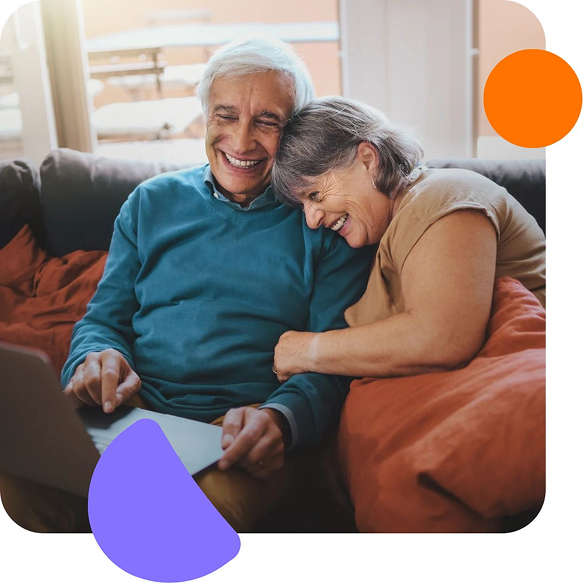 Smiling elderly couple sitting on a couch, looking at a laptop together, with colorful abstract shapes around the image.